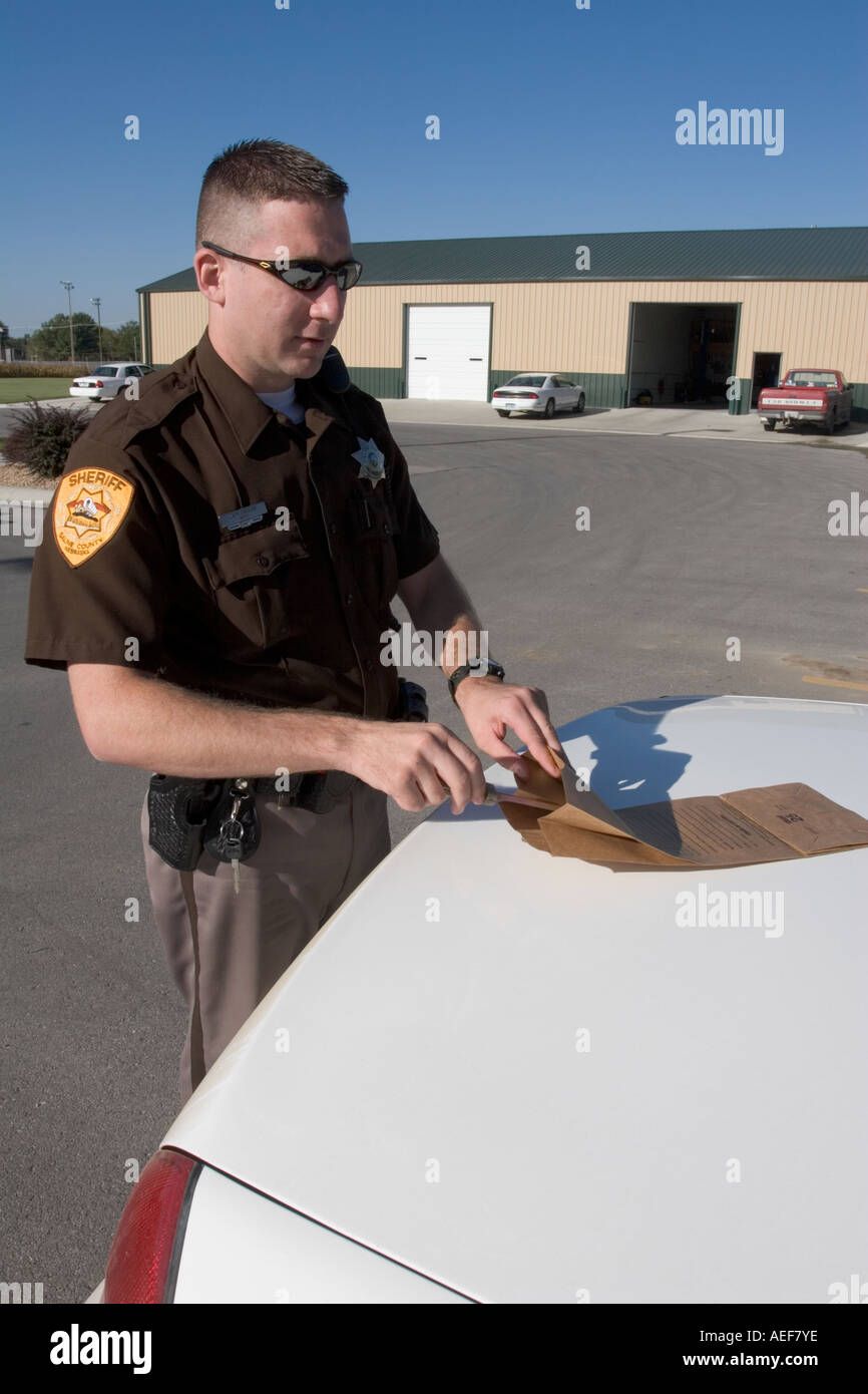Sheriff s deputy placing evidence in evidence bag Stock Photo