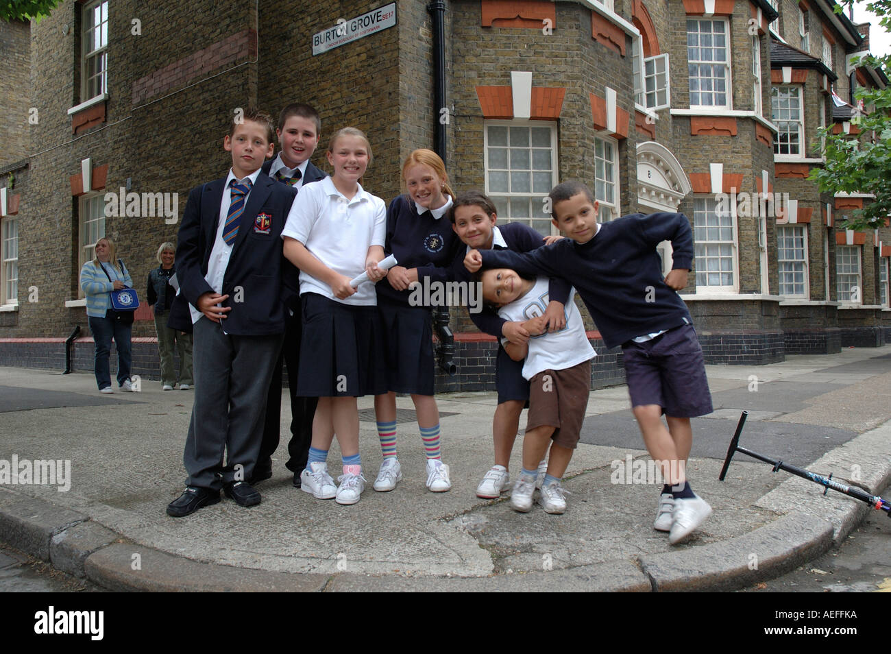 Mixed age group of children posing in the street on way home from school Stock Photo