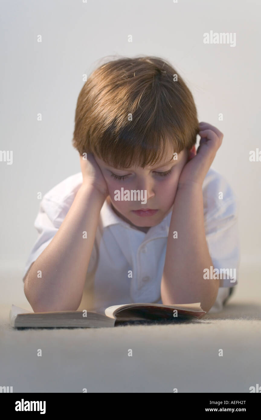 A young schoolboy in deep concentration reading a book Stock Photo
