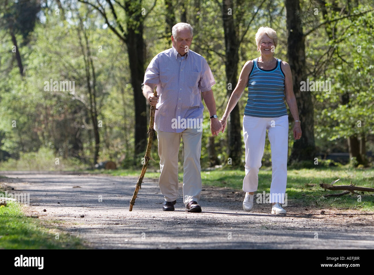 Smiling couple walking hand hand through forest hi-res stock ...