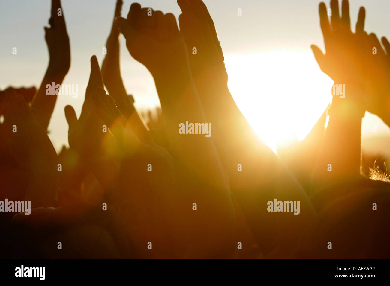 sun setting at open air concert through fans waving their arms in the air Stock Photo
