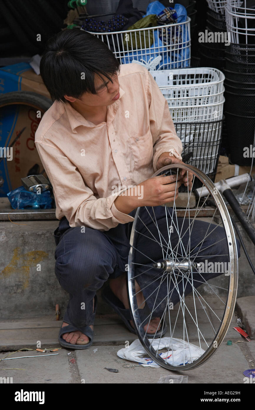 Man fixing bike wheel, China Beijing Xicheng District Zhengjue Hutong Stock Photo