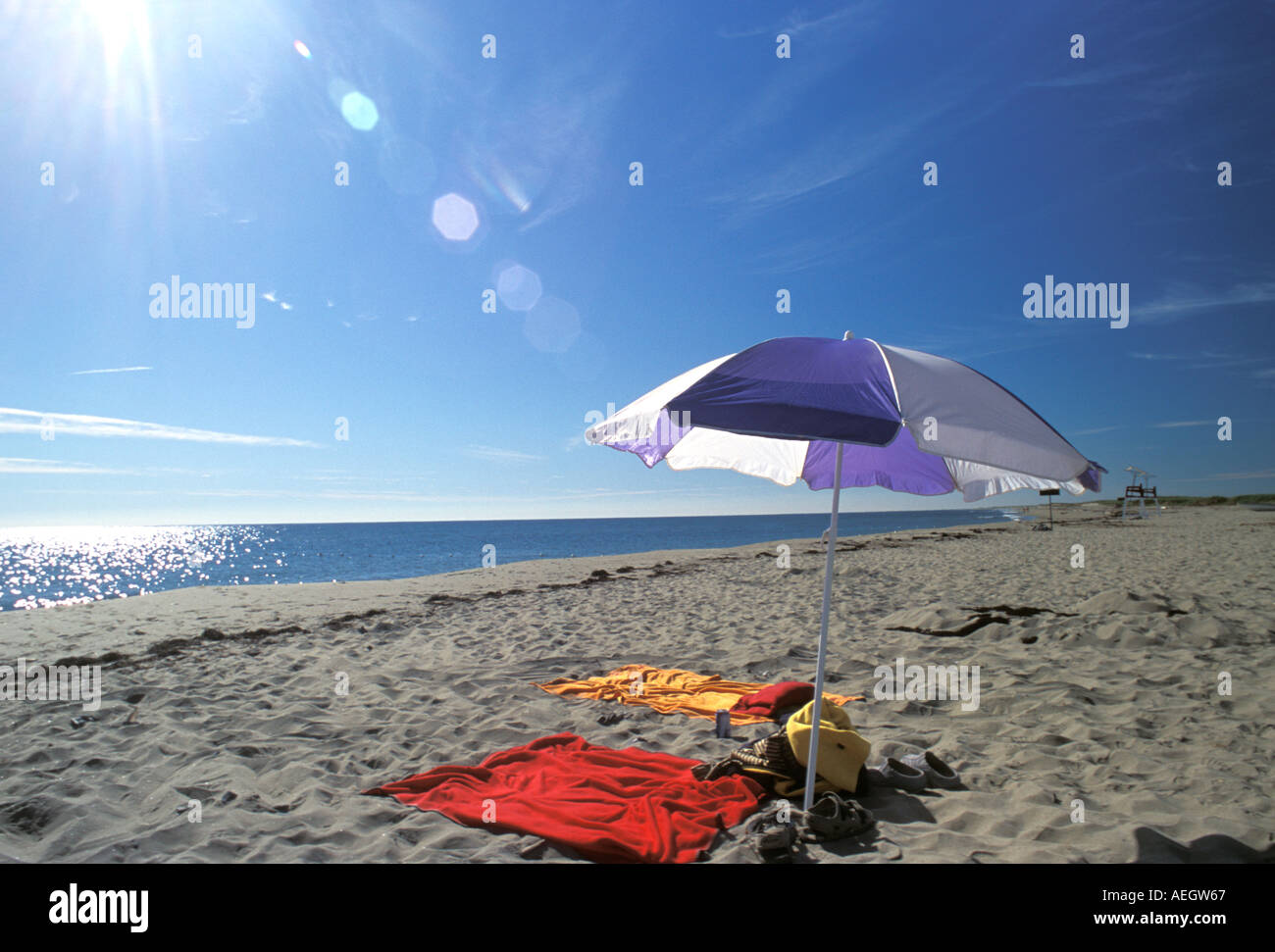 Purple and white beach umbrella stuck in the sand with two beach