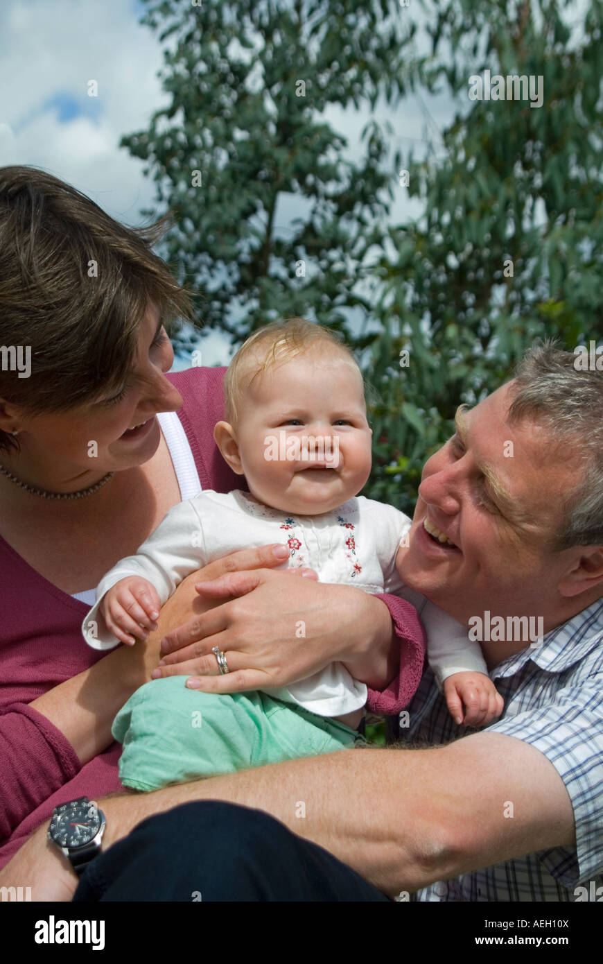 Vertical close up portrait of a young family, (mum, dad and six-month ...