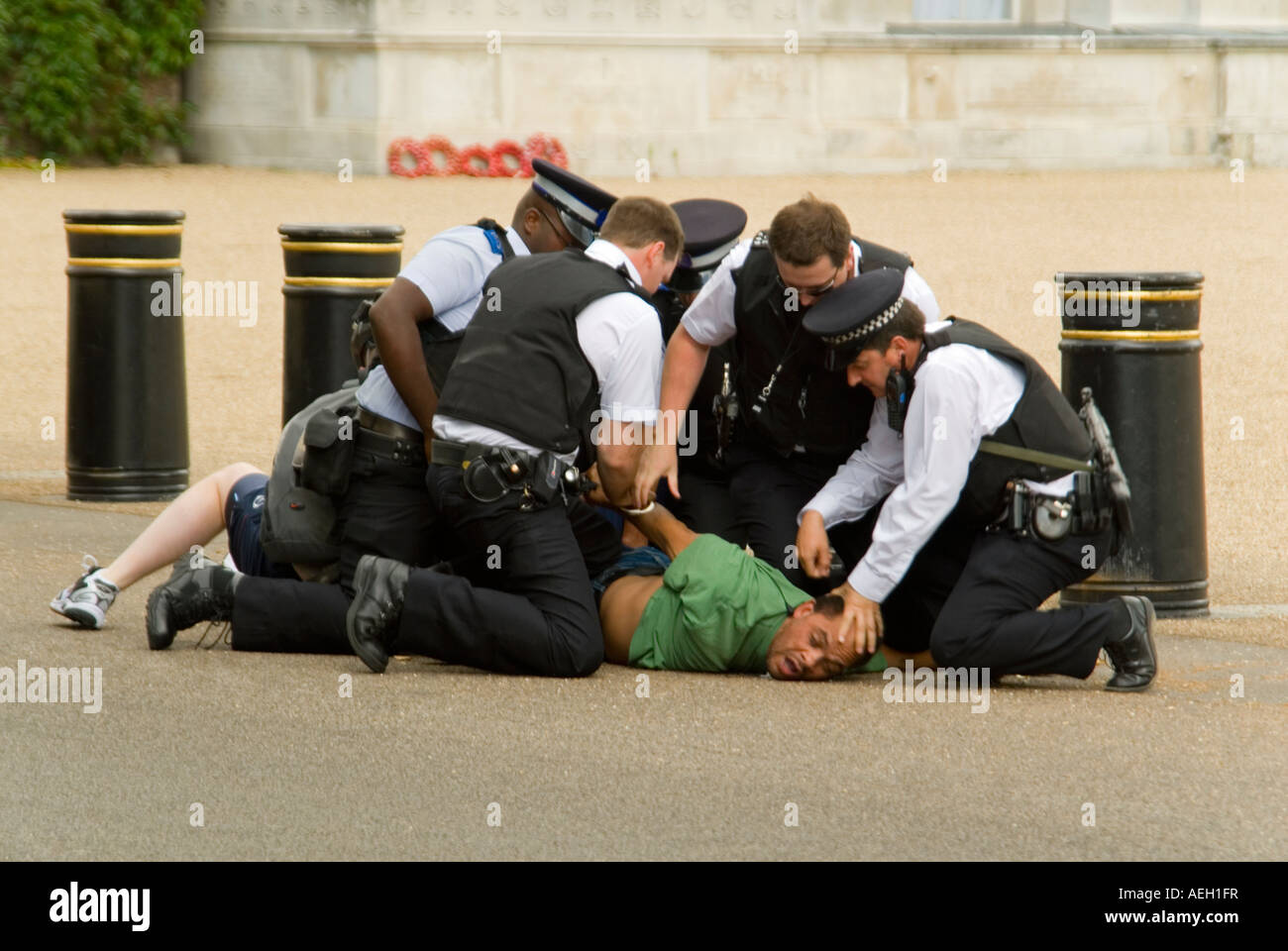 Horizontal close up of a man being restrained by several policemen in central London after