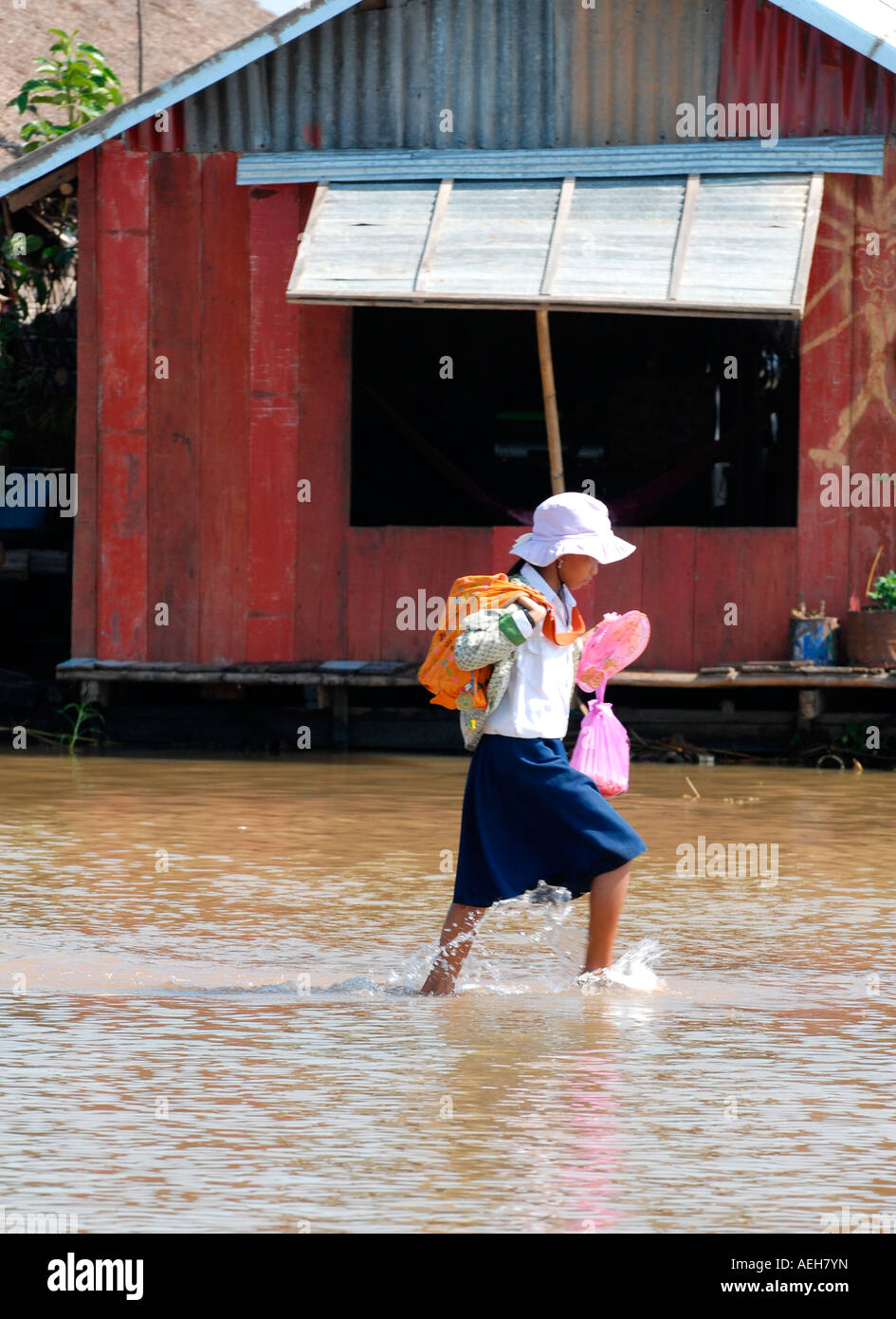 Cambodia , Siem Reap , Tonle Sap Lake , Phnom Krom , sweet young village girl in uniform wades home from school on flooded path Stock Photo