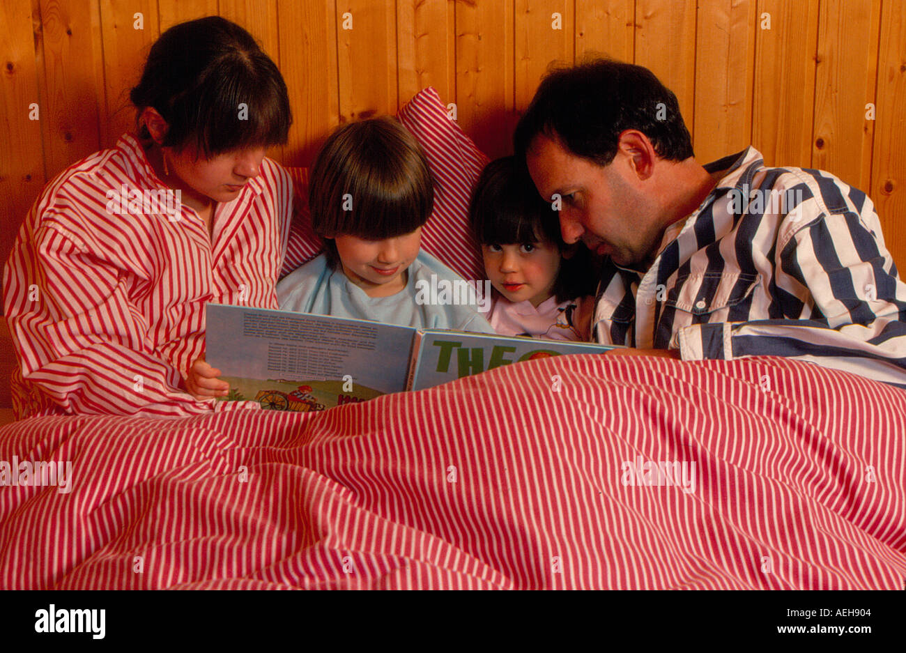 family reading a child book in bed. Photo by Willy Matheisl Stock Photo