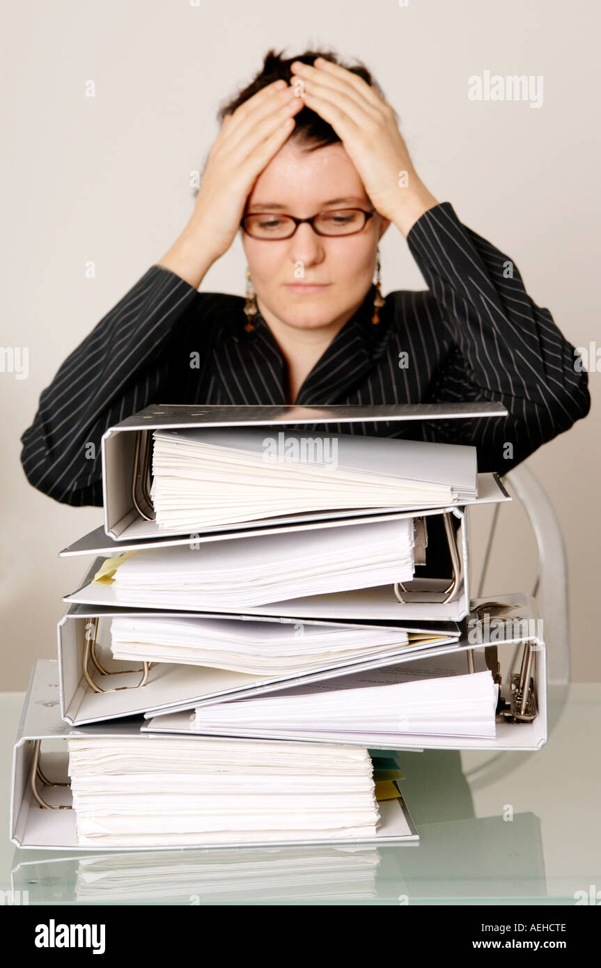 Mid adult woman with files on desk head in hands Stock Photo Alamy