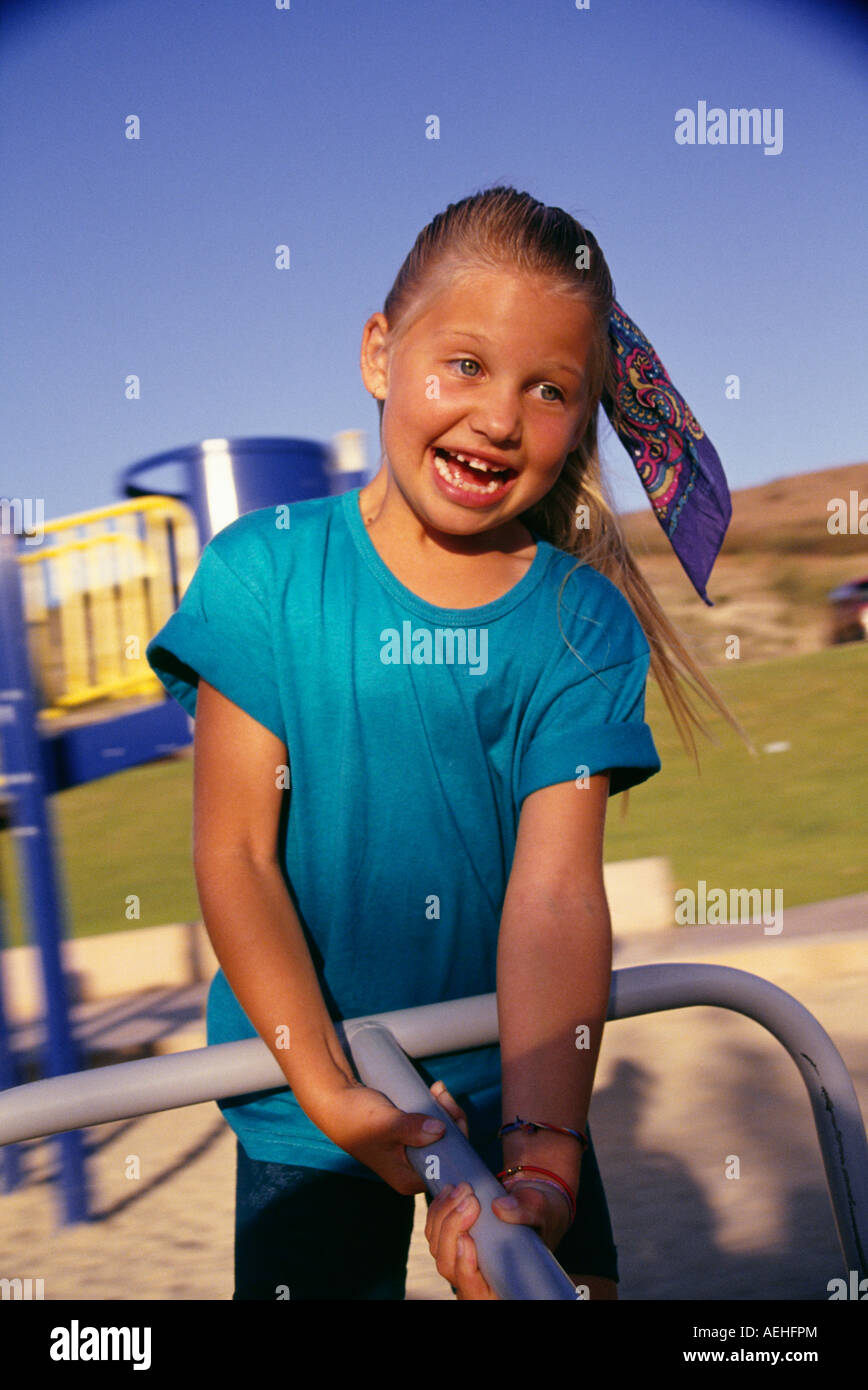 Girl 7-9 years old holding onto moving spinning playground merry-go-round   MR  © Myrleen Pearson.  .......Ferguson Cate Stock Photo