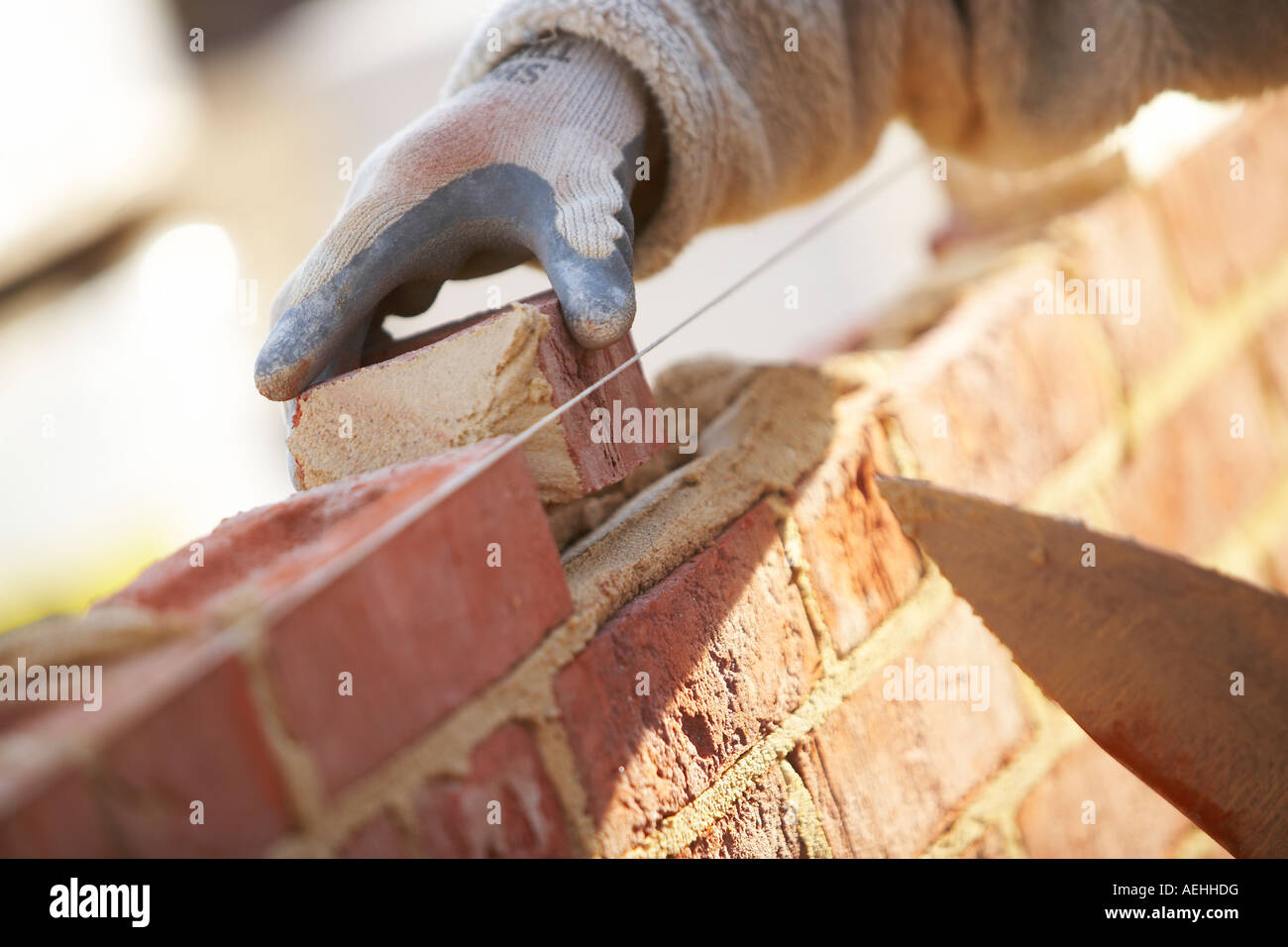 WORKERS HANDS WITH TROWEL LAYING BRICKS WITH MORTER ON A CONSTRUCTION SITE IN THE UK, BUILDING Stock Photo