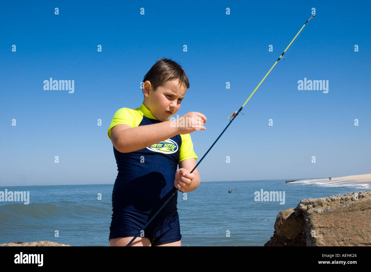 Young white boy baiting a hook to fish in the Indian Ocean off of Mozambique Stock Photo