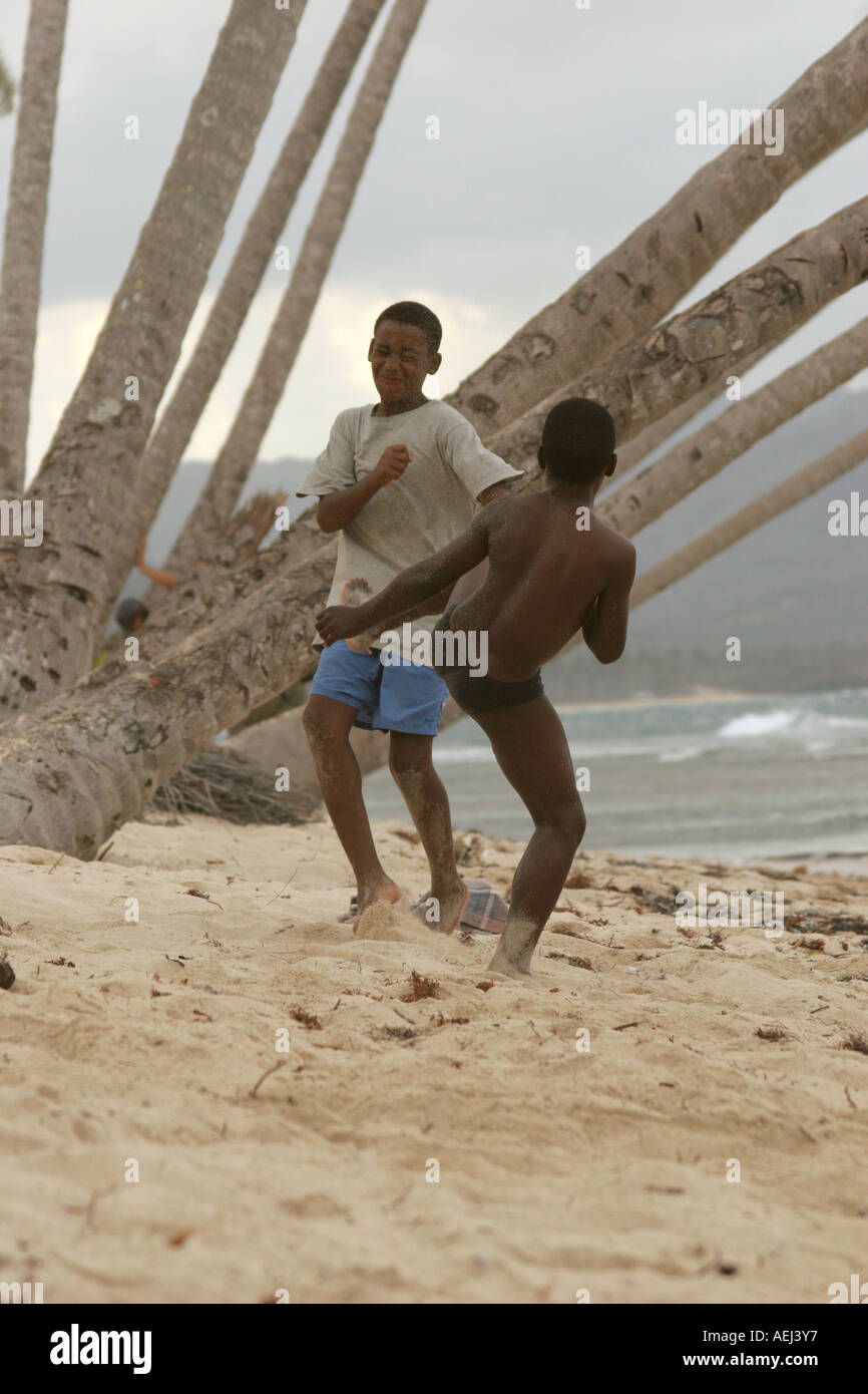 Two black dominican boys fighting in a beach One of them is kicking