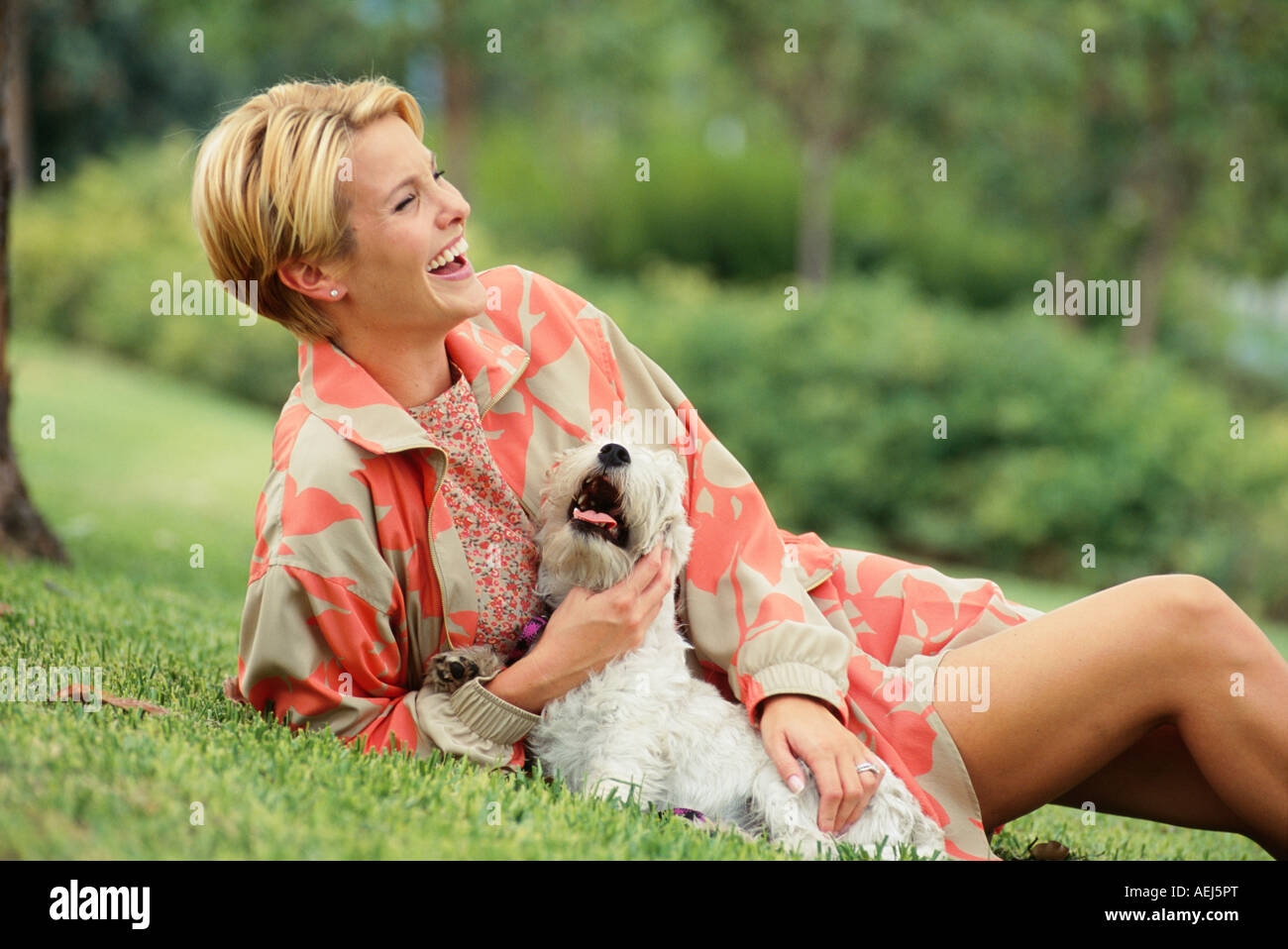 Woman lying on grass with dog Stock Photo - Alamy