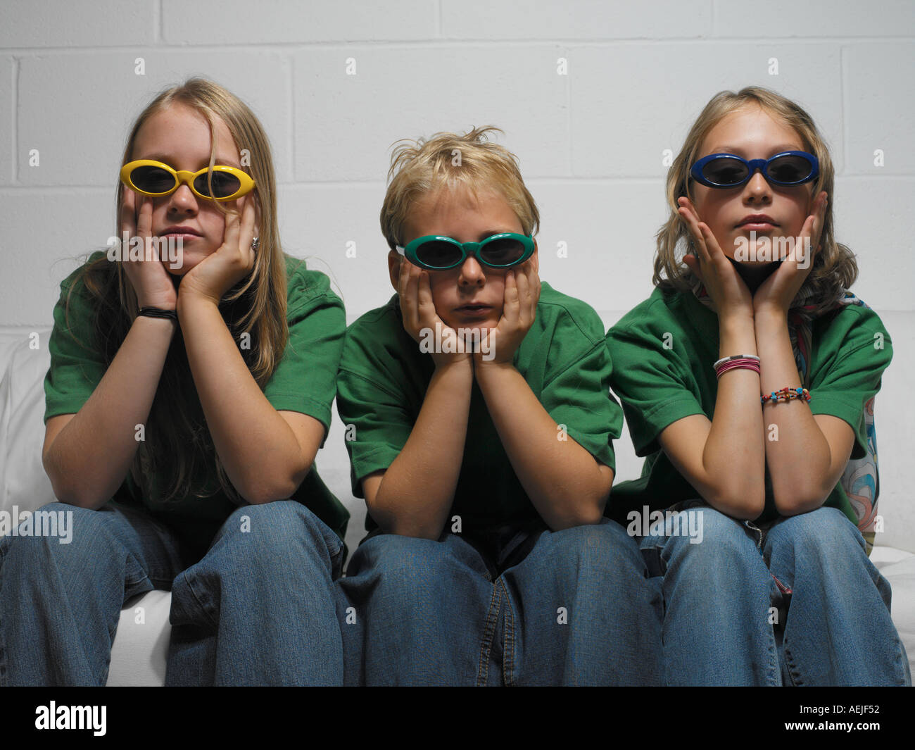 three adolescents sitting on white sofa Stock Photo