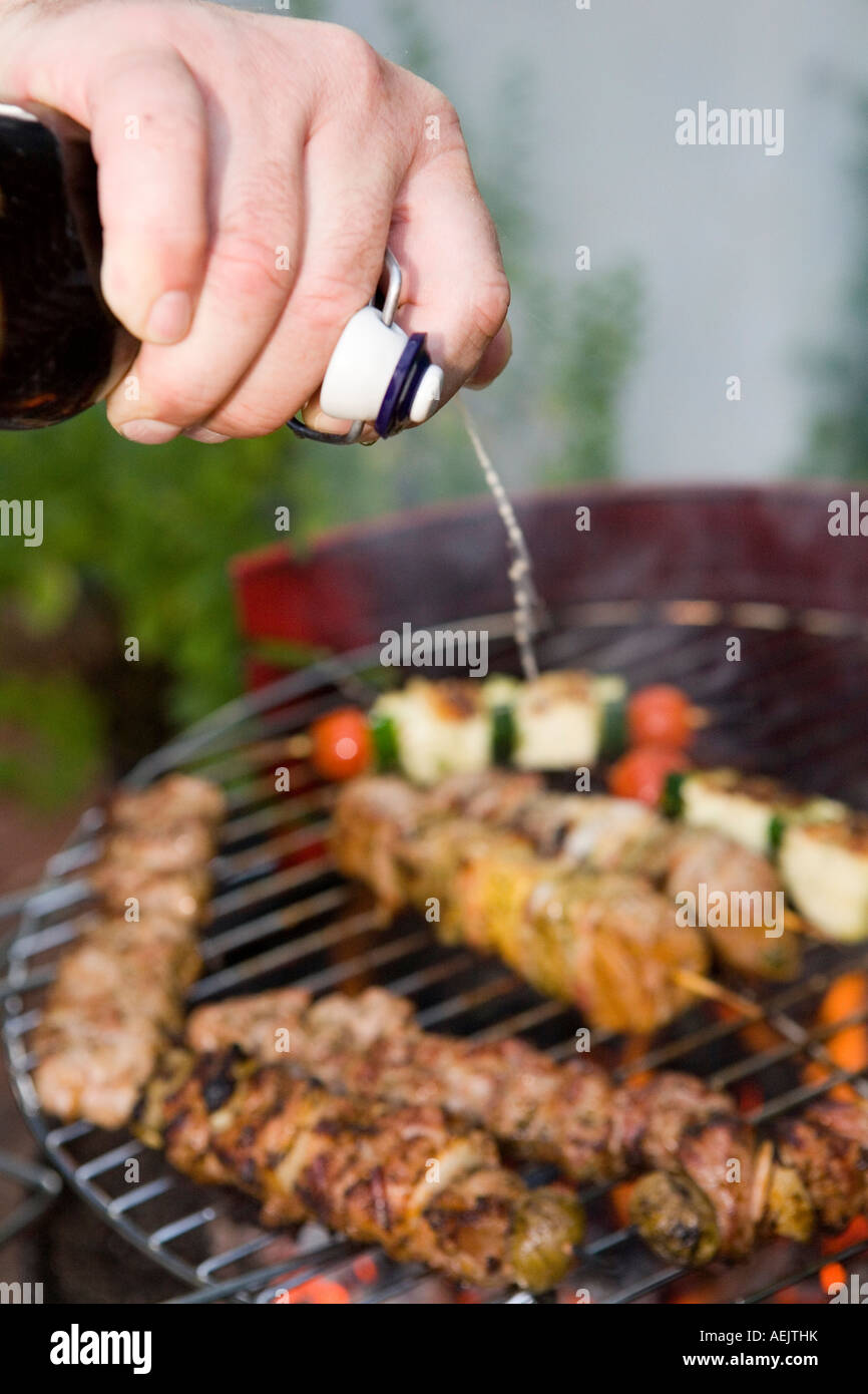 Meat spits on a grill, moistened with beer Stock Photo Alamy
