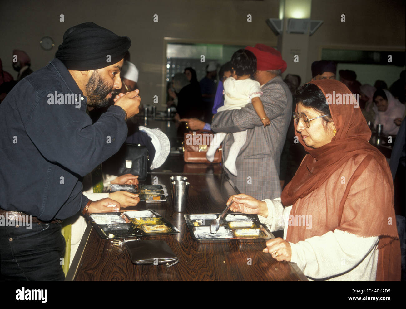 Sikhs sharing langar the vegetarian  meal served after Sunday service in the Gurdwara Stock Photo