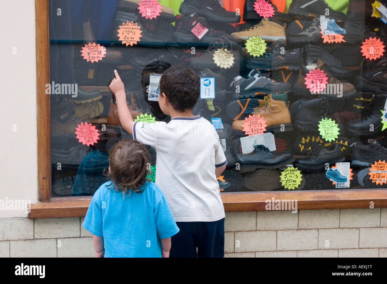 Little boy helping his sister to choose a new pair of shoes from a shoe shop window Stock Photo