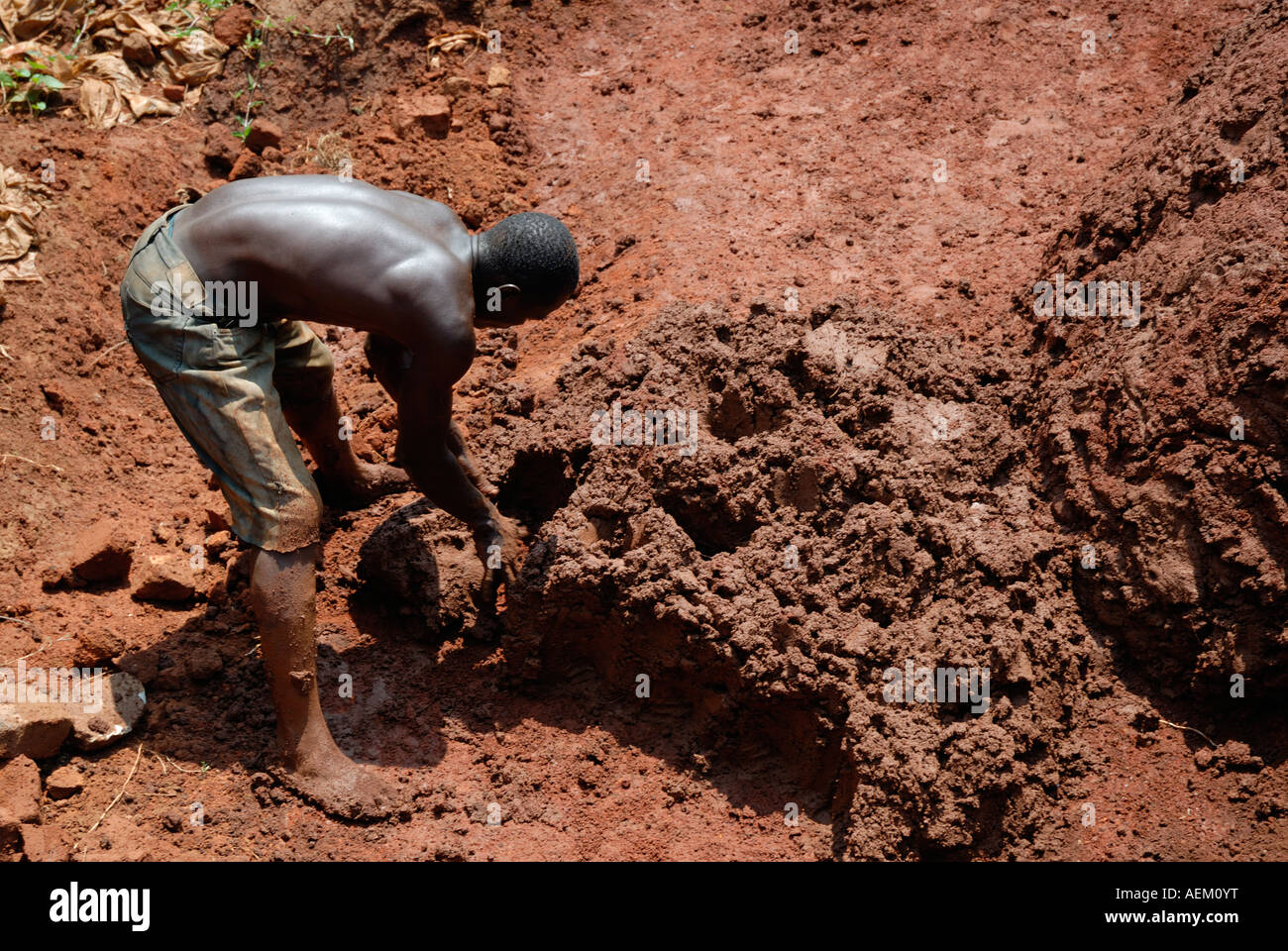 Young balck African man mixing the clay to make bricks in Western Kenya at the side of the Kisumu Maseno road in Kenya Stock Photo