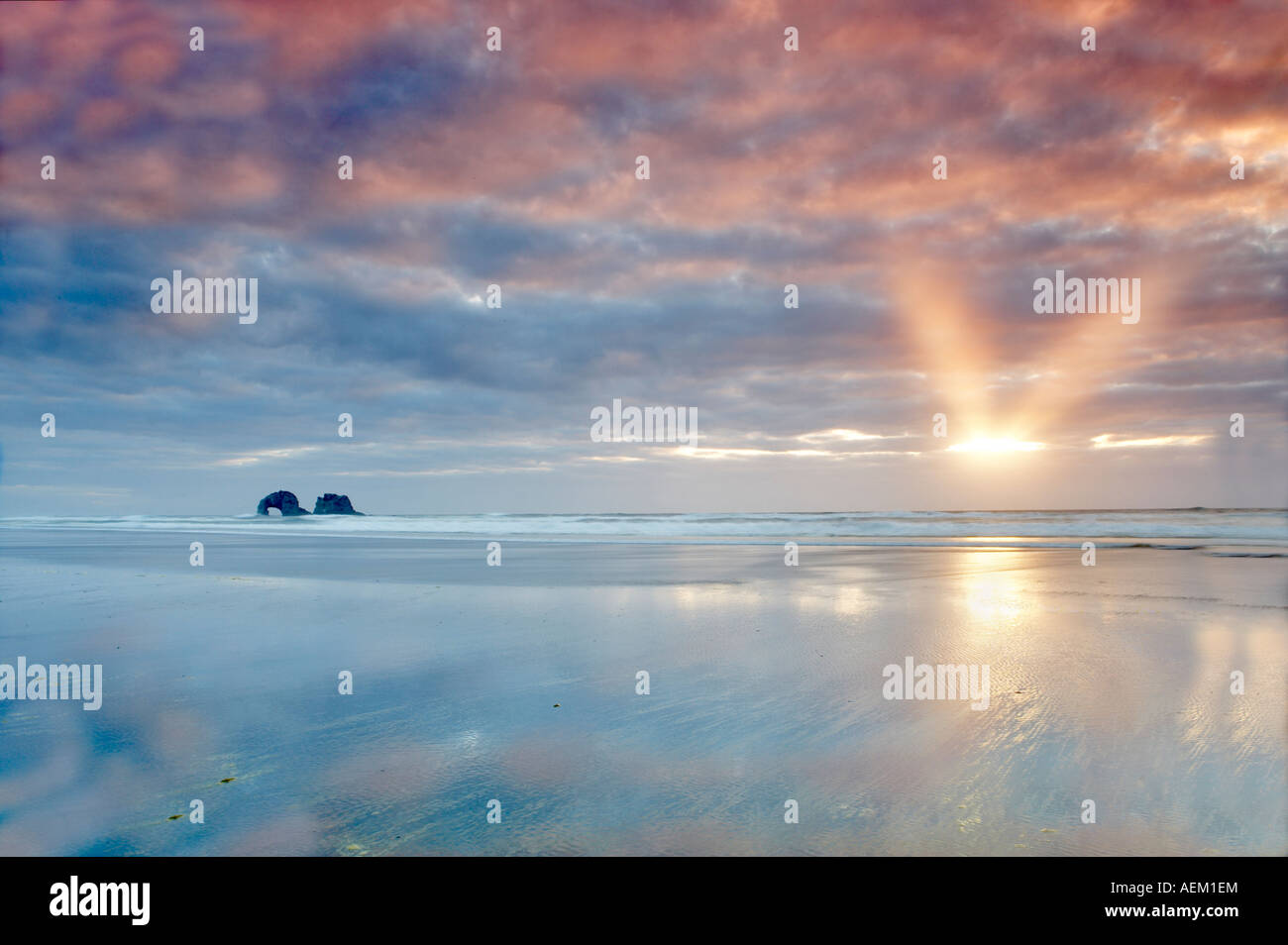 Low tide reflection with sunburst and arch Rockaway Beach Oregon Stock