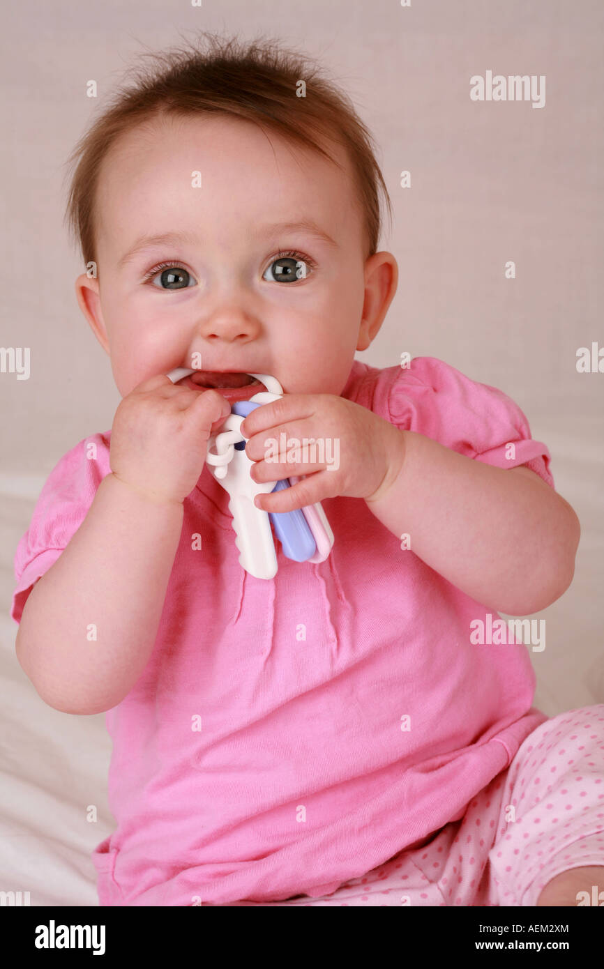 Cute adorable newborn baby girl at 7 seven months chewing biting on a set of teething keys