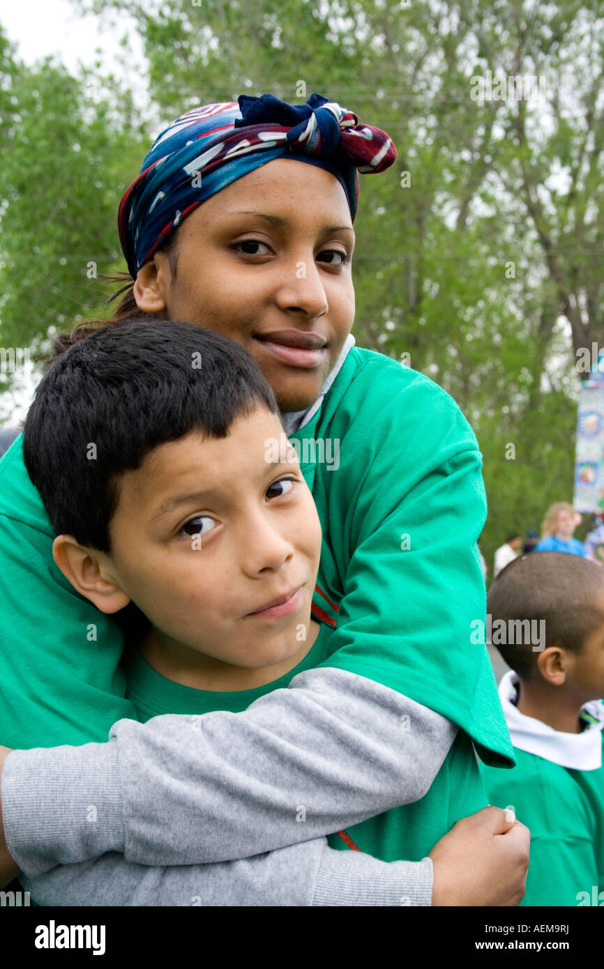 Affectionate Latina woman embracing son age in Boys and Girls Club parade unit. Cinco de Mayo Fiesta. 'St Paul' Minnesota USA Stock Photo