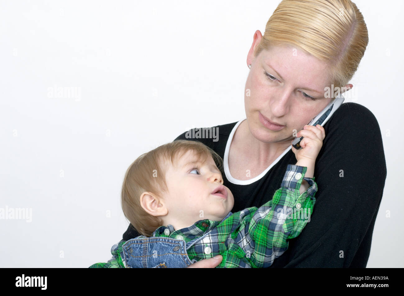 Baby grabs cell phone as mother talks Stock Photo Alamy
