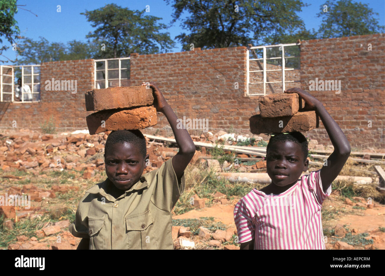 Zimbabwe Mola near Kariba, Boy and girl carrying bricks for building school Stock Photo