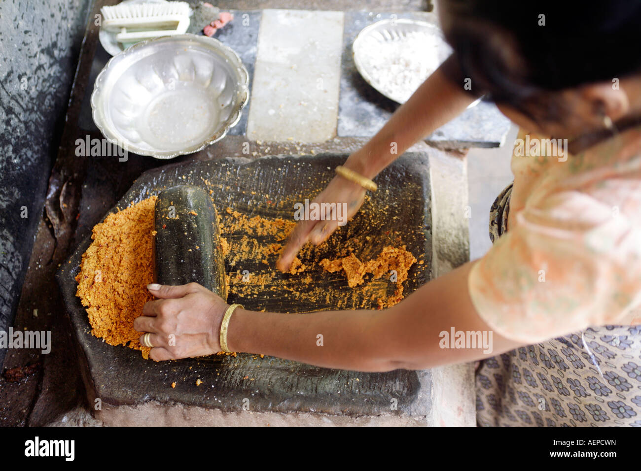 Goan Indian woman grinding coconut and chillies for curry with flat