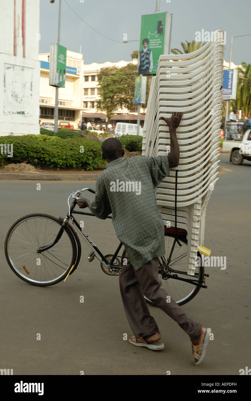Luo man pushing a bicycle heavily loaded with a towering pile of