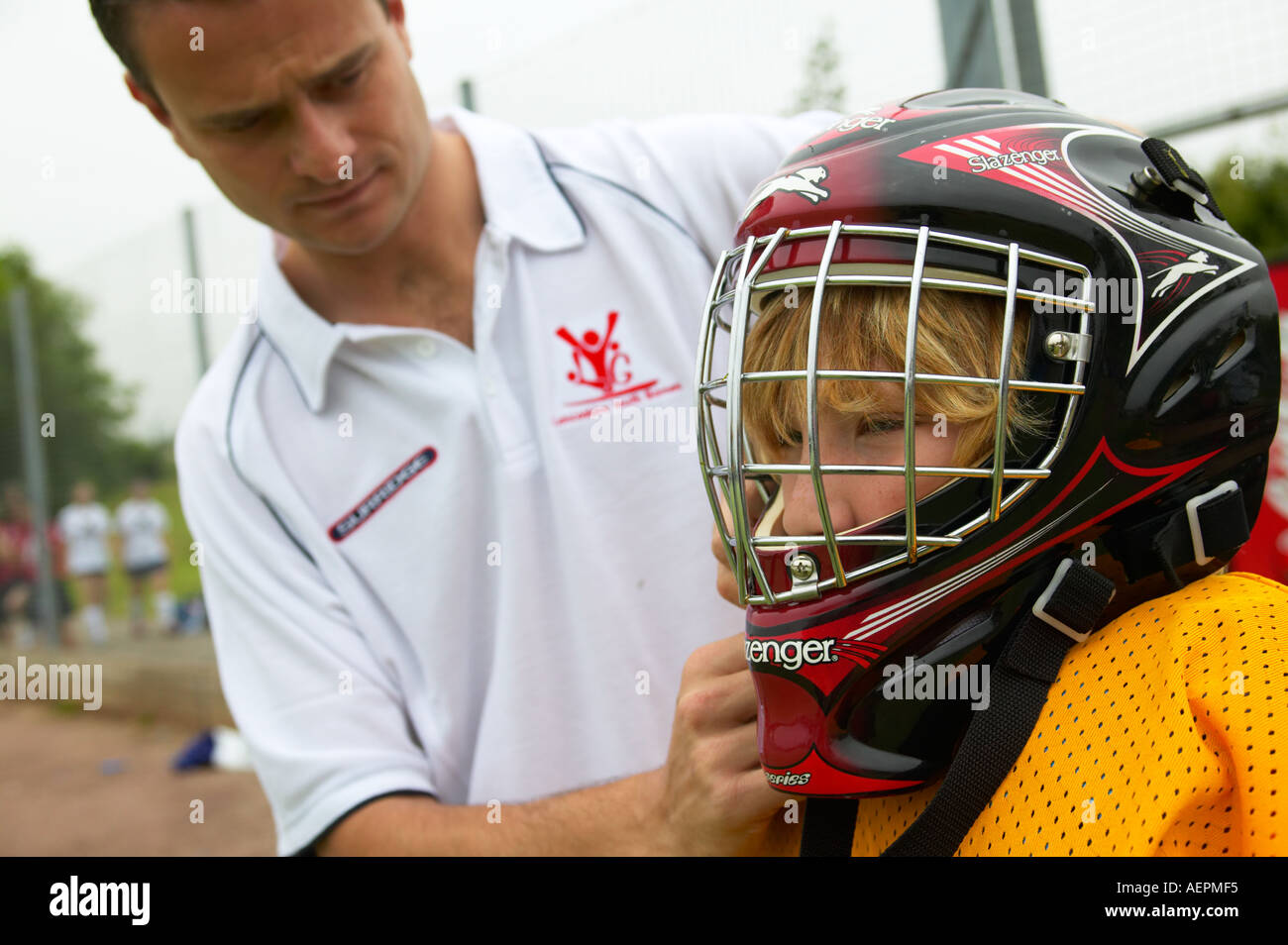 Coach fitting helmet to hockey goalkeeper Stock Photo