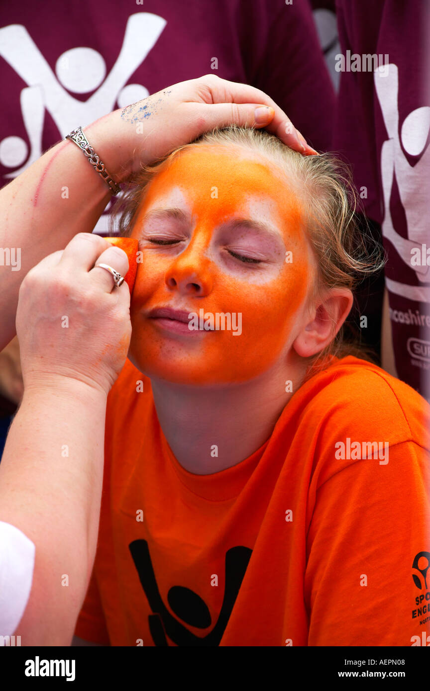 young girl having her face painted at a sports event Stock Photo