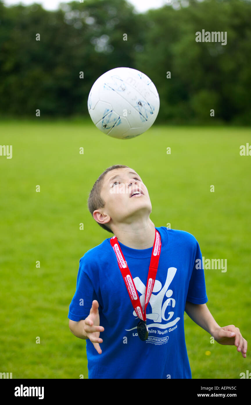young boy bouncing football on his head Stock Photo Alamy