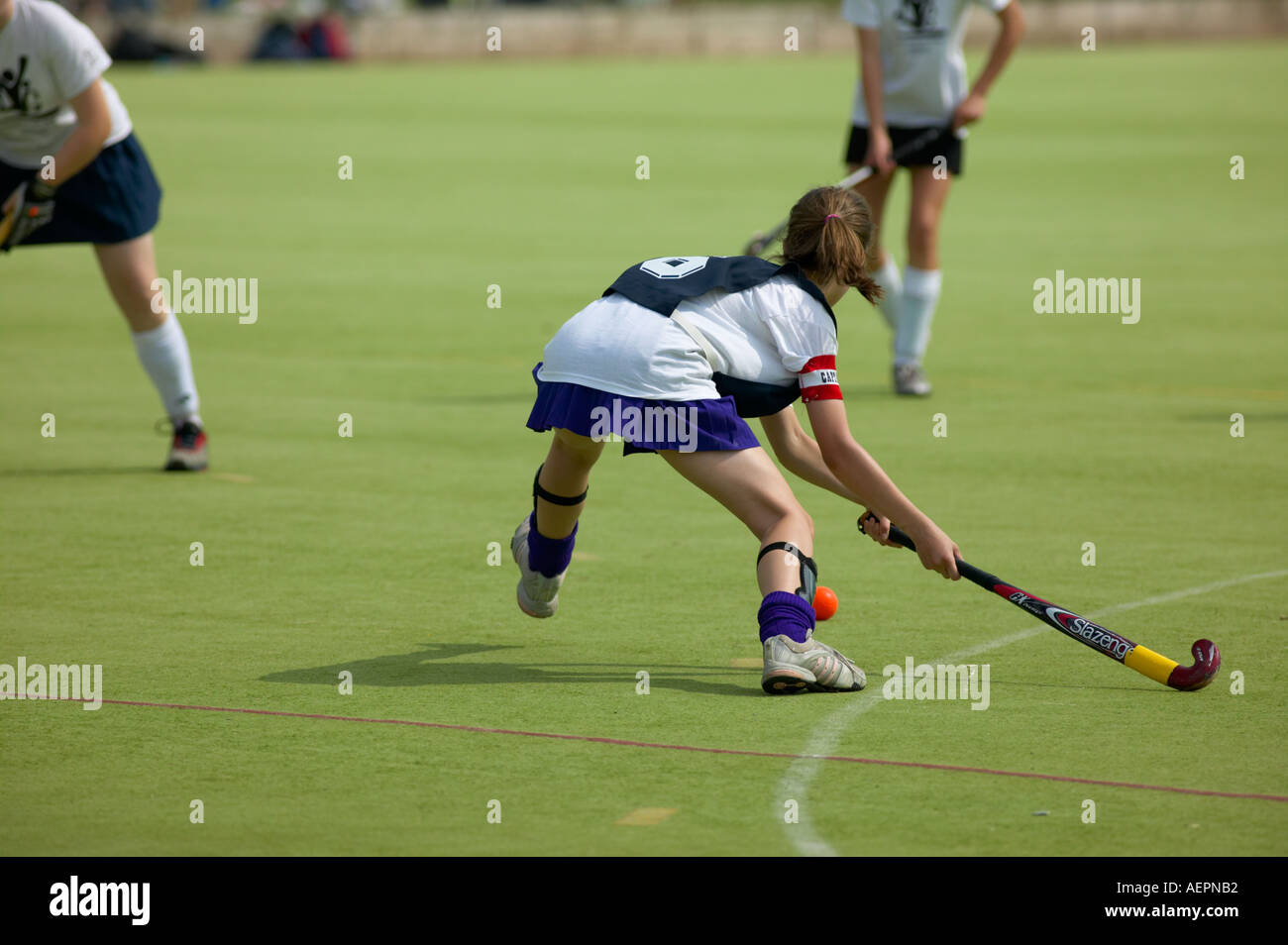 Striking the ball in a hockey match at a sports day event Stock Photo