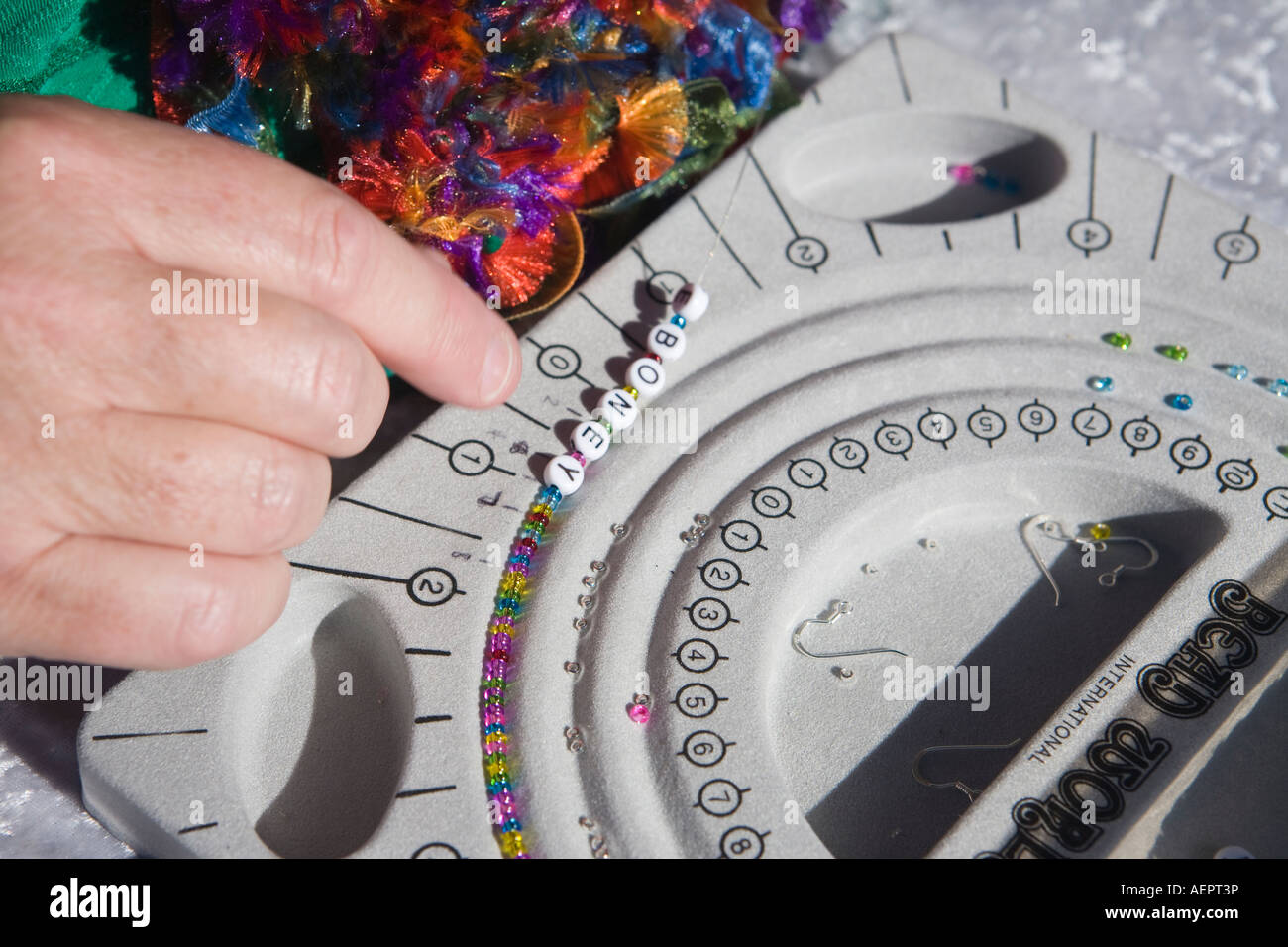 Threading alphabet beads on a delicate beaded necklace Stock Photo Alamy
