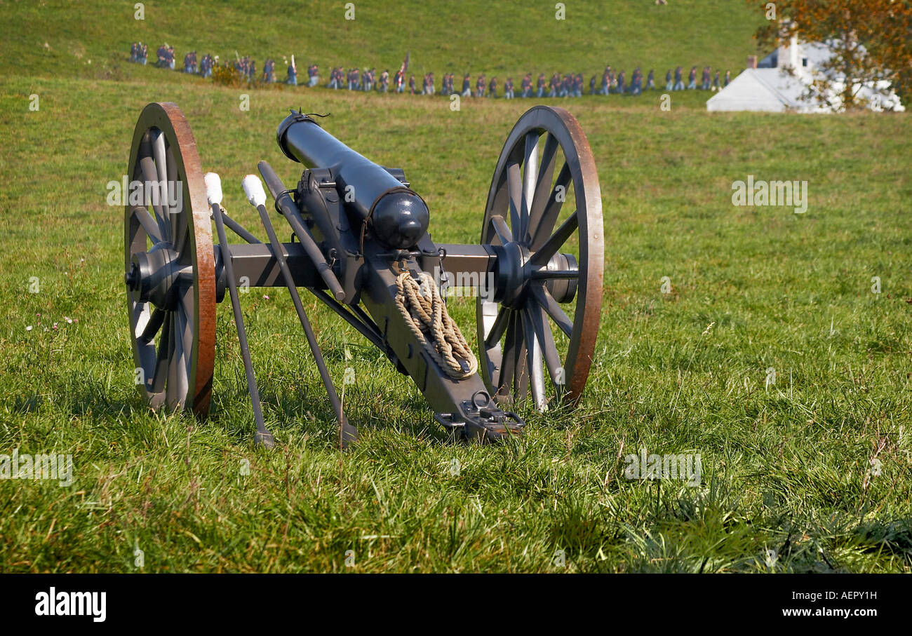 Confederate cannon on the battlefield Union troop reenactors in the background Stock Photo