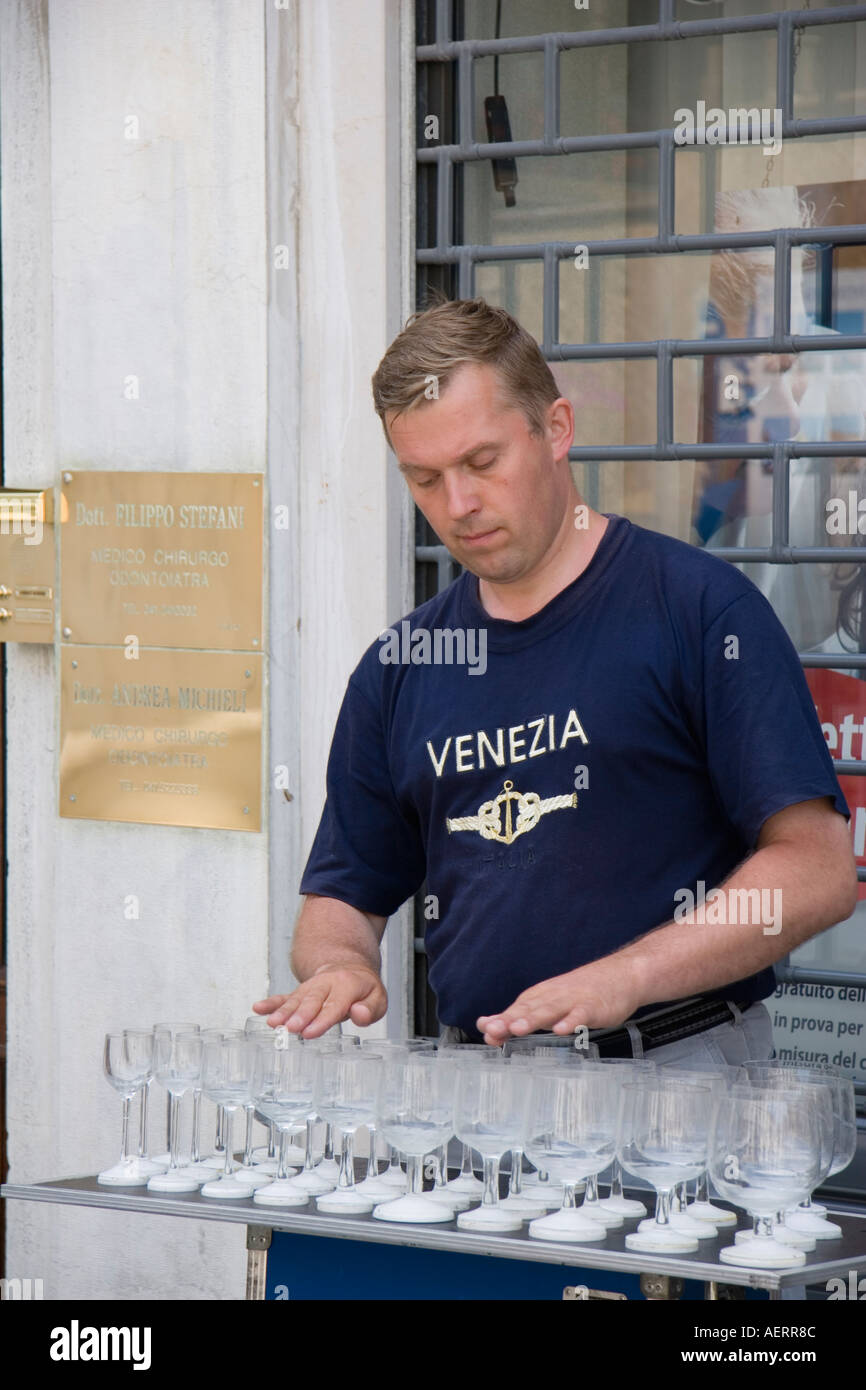 Musician using hands and wet fingers to play wine glass musical