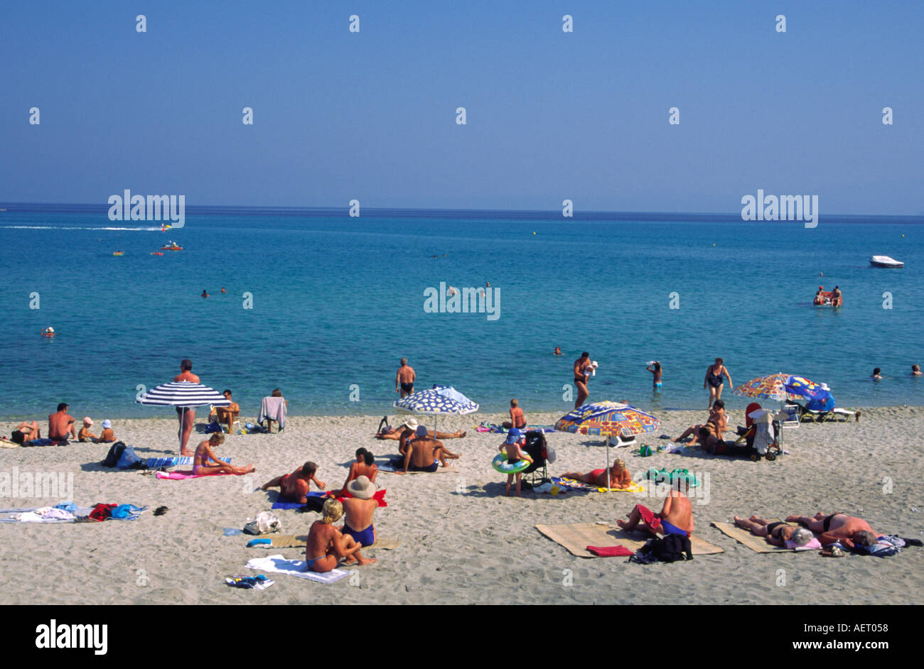 Holiday makers sunbathing on the beach beside the Aegean Sea at Hanioti Kassandria Chalkidiki Greece Stock Photo
