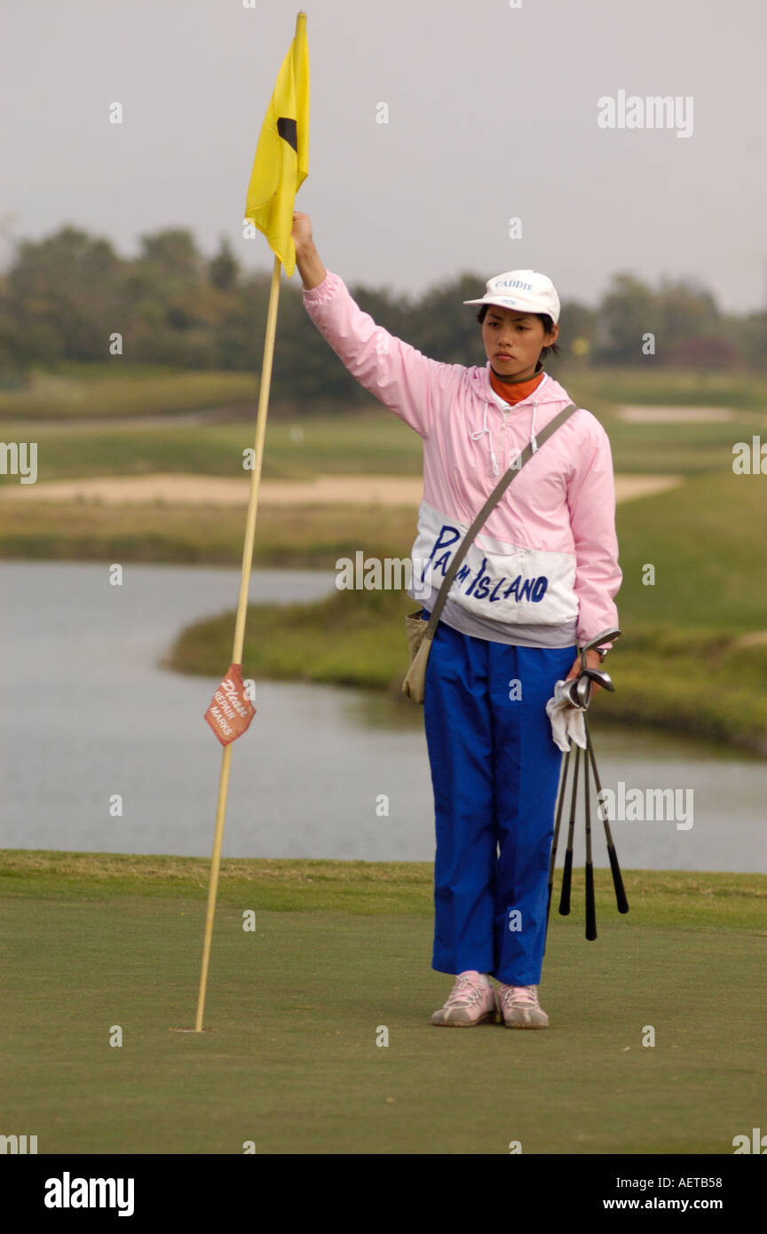 A Trainee golf caddy holding a flag pin on a green at a golf resort in Guangdong Province in China 2005 Stock Photo