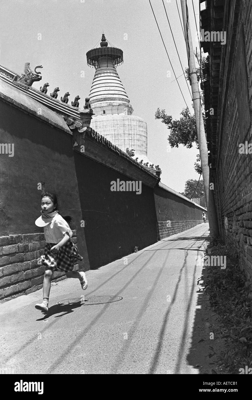 A schoolgirl running in a small hutong next to the White Cloud Temple in Beijing 2003 China Stock Photo