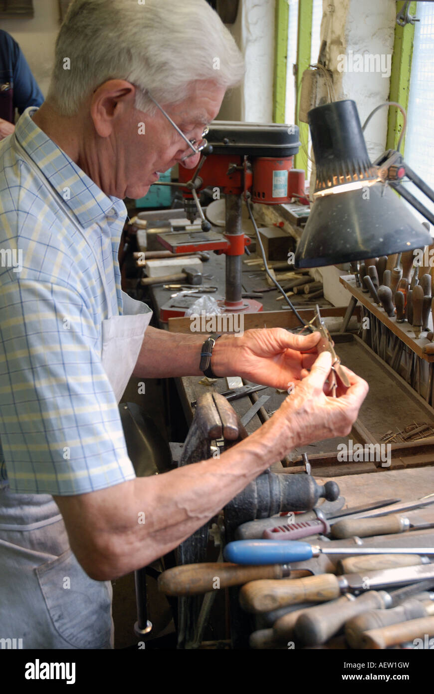 Stan Shaw at his workbench examining a fishing knife Stock Photo