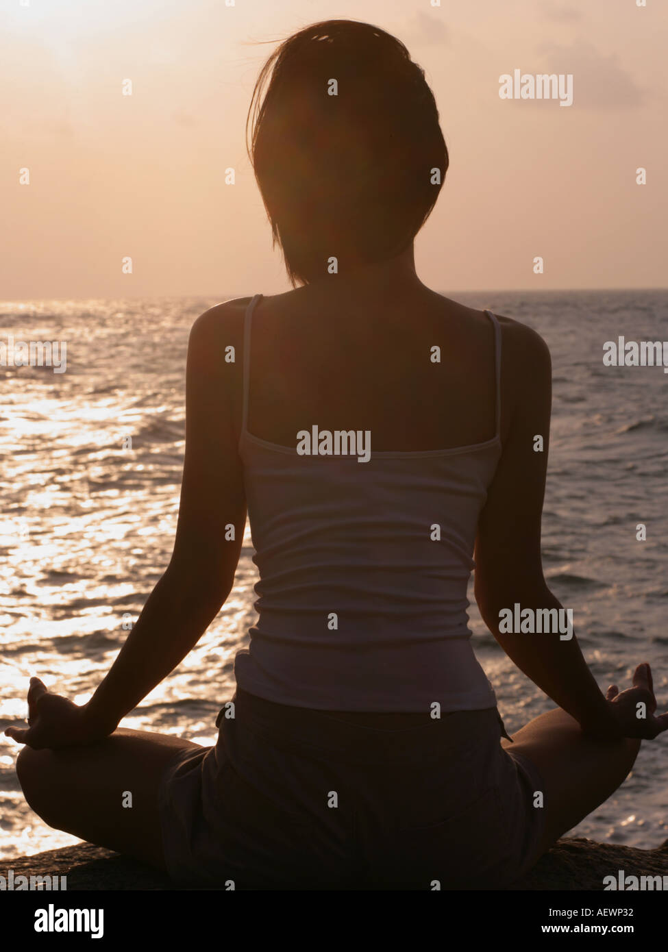 Rear view of a woman meditating on the beach Stock Photo - Alamy