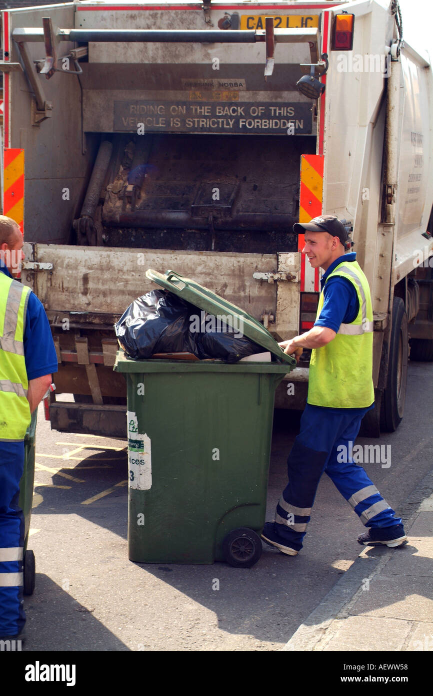 Large green commercial dustbin being wheeled to the truck for emptying