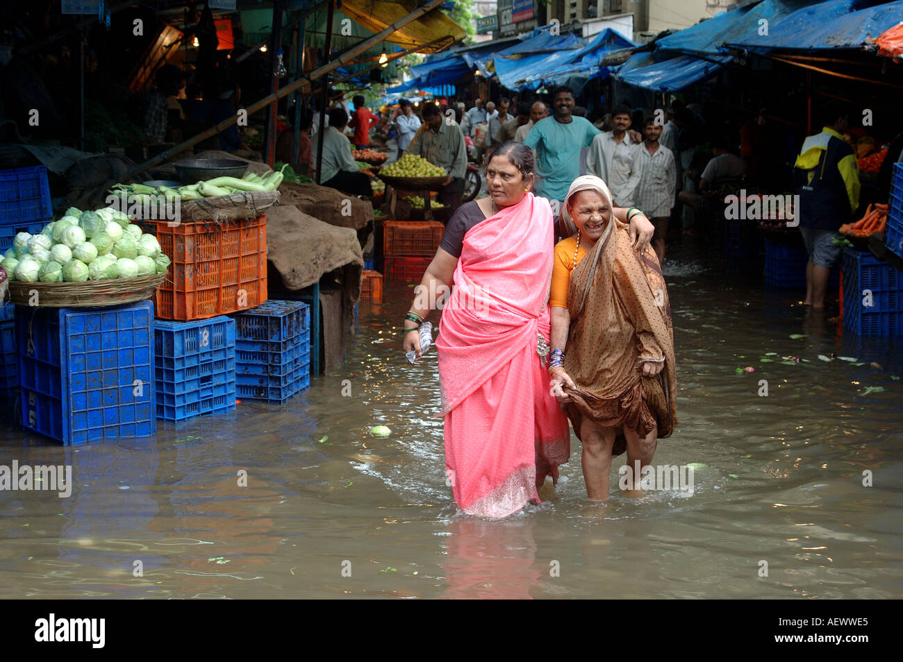 two indian women walking in monsoon rain water in vegetable market of Bombay now Mumbai India Stock Photo