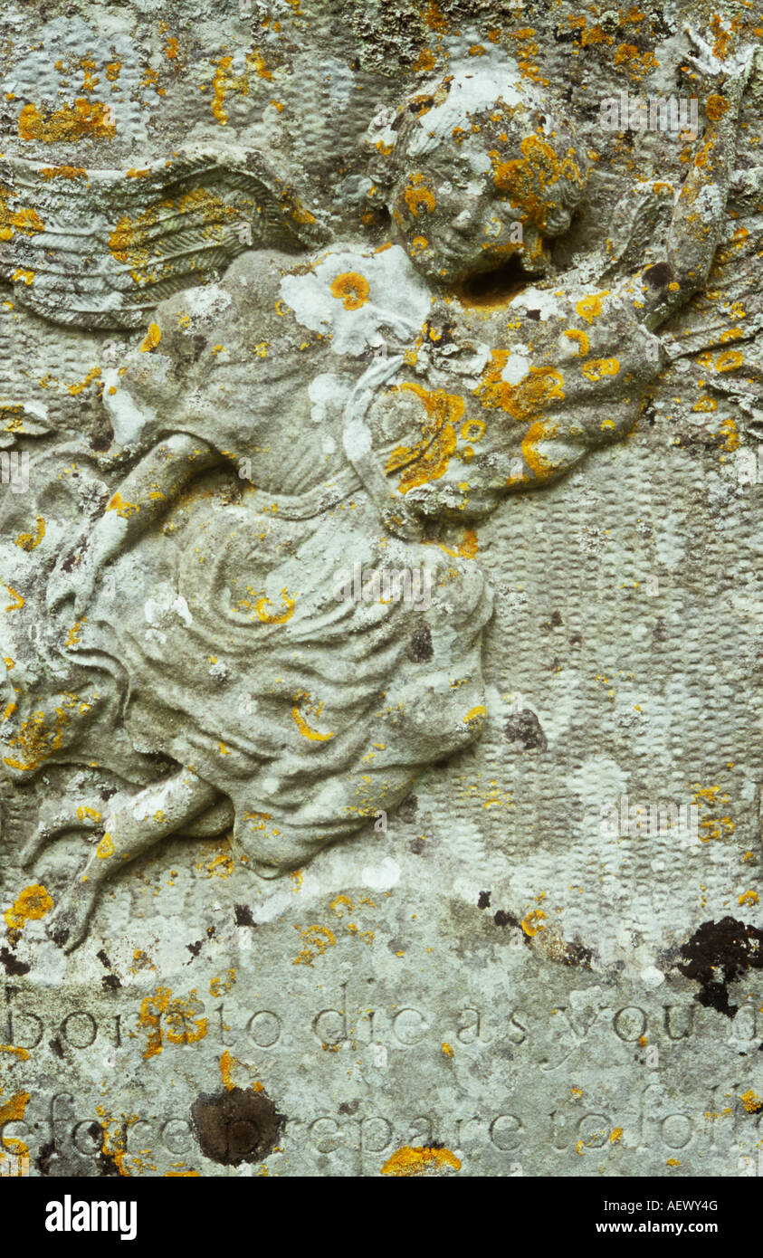 Detail of lichen-covered limestone gravestone with carving of young female angel flying heavenwards with billowing robe Stock Photo
