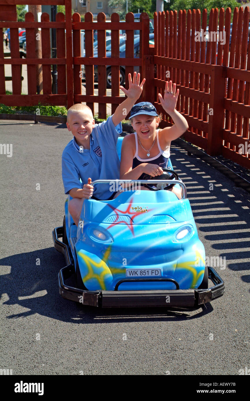Children having fun driving go-karts around a track at an amusement park Stock Photo