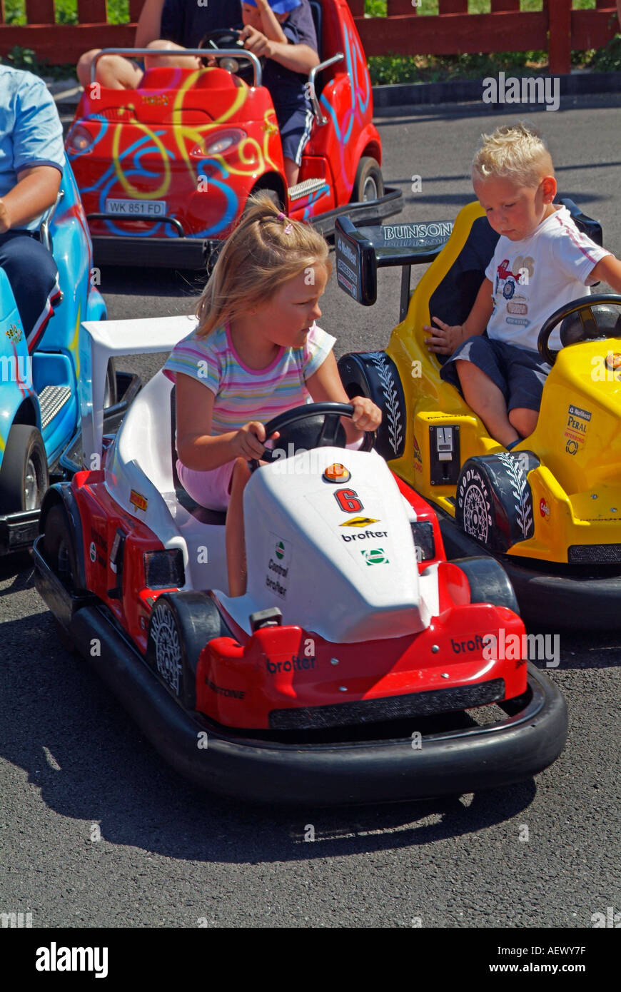 Children having fun driving go-karts around a track at an amusement park Stock Photo