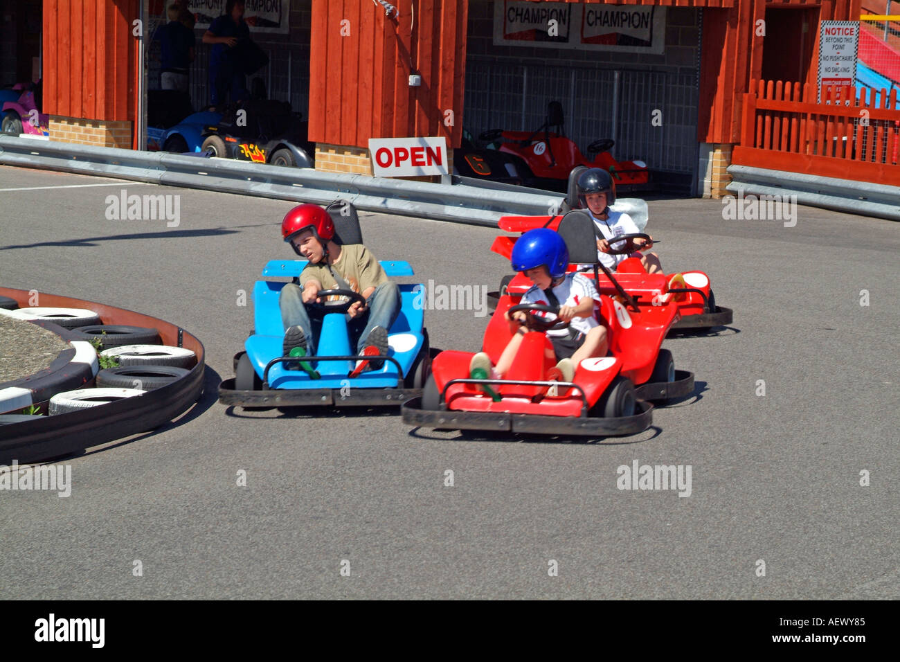 Children Having Fun Driving Go Karts Around A Track At An