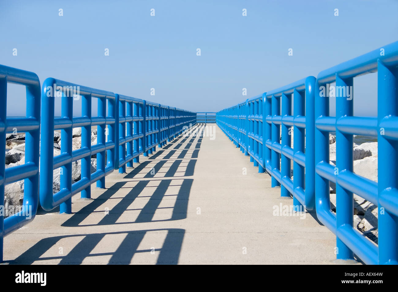 Concrete walkway bounded by blue safety rails Stock Photo