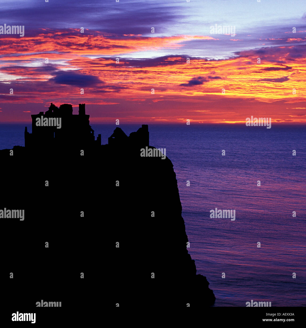 Square format image of a silhouetted Dunnottar castle near stonehaven north east scotland Aberdeen with vibrant sunrise skies. Stock Photo