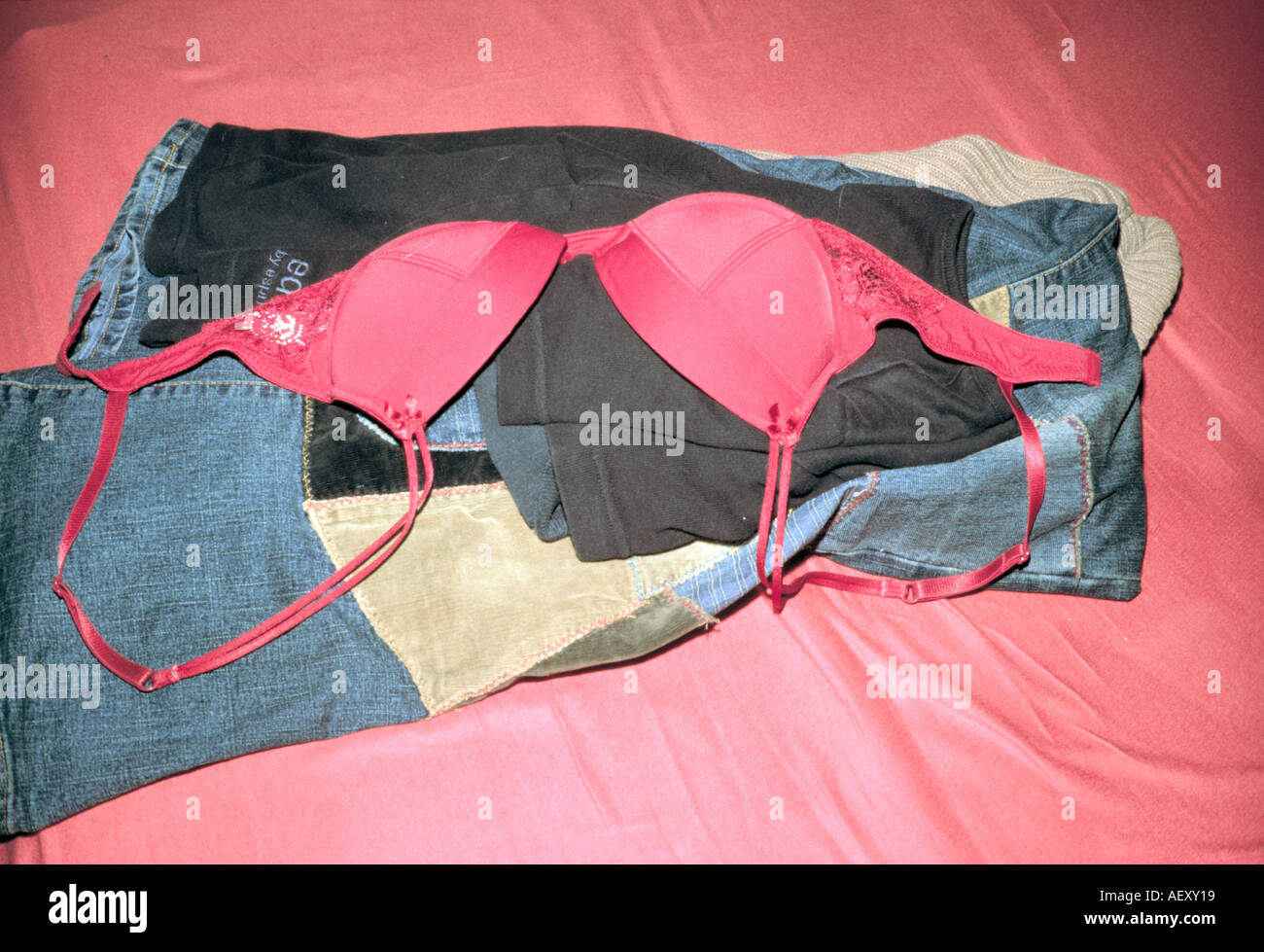 Blue jeans sweaters and a bra lying on a bed Stock Photo - Alamy